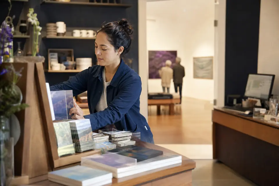 Volunteer arranging books and cards in a small museum gift shop