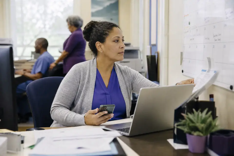 Finance manager checking a wall calendar at her desk in a nonprofit office