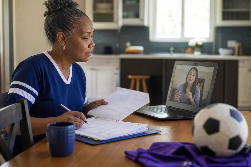 Volunteer treasurer at a kitchen table reviewing records during a video call
