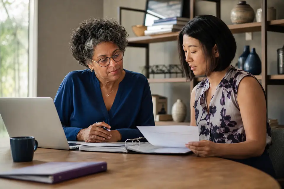 Foundation trustee and preparer reviewing investment statements in a small office