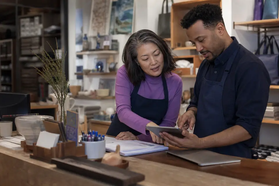 Museum manager and preparer reviewing gift shop sales on a tablet after hours